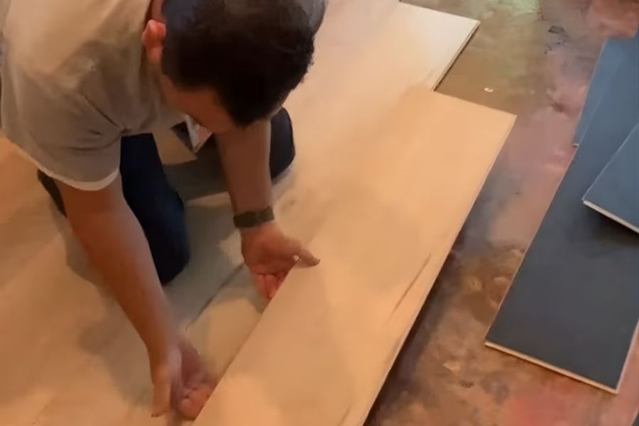 Restoration technician carefully removing laminate flooring planks to assess water damage underneath