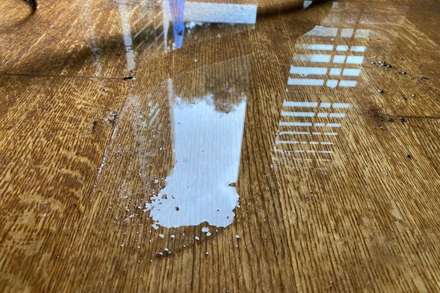 Standing water pooling on wooden flooring surface showing early stage water damage