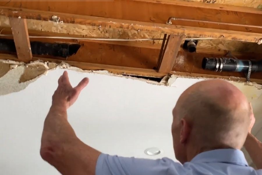 Ceiling damage from an improperly handled sewage backup showing exposed pipes and water staining