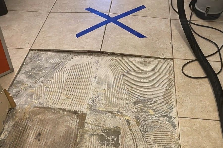 Tile removal showing water damage underneath a Newport Beach home floor
